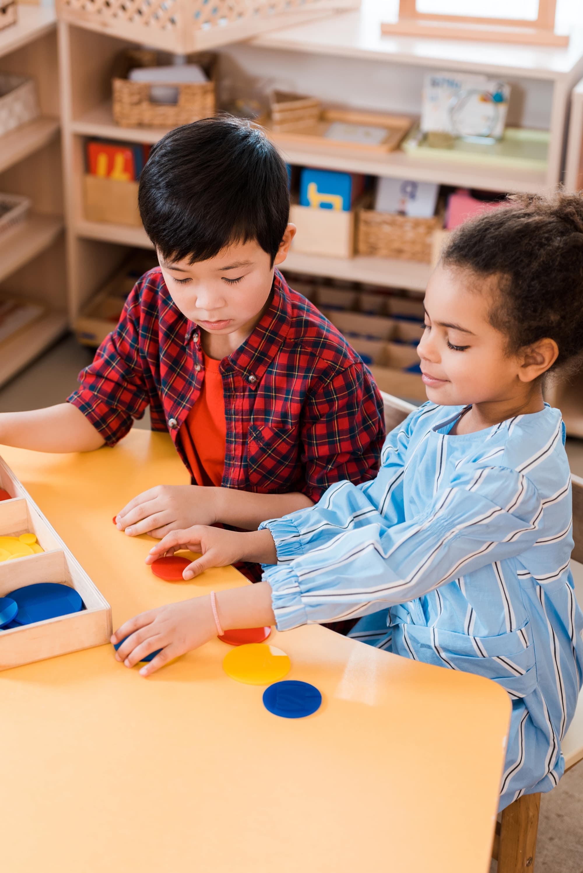 Two children working together with coloured Montessori discs